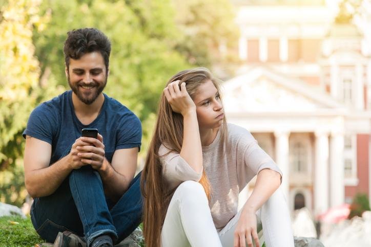 Hombre prestandole atencion al telefono y no a su pareja que esta aburrida